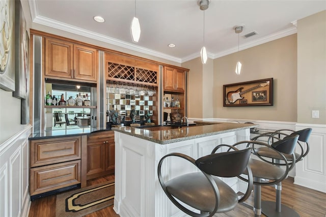 bar with dark wood-type flooring, pendant lighting, dark stone counters, and crown molding