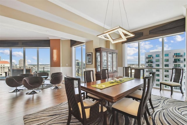 dining space with a wealth of natural light, hardwood / wood-style floors, and ornamental molding