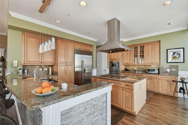 kitchen featuring sink, kitchen peninsula, built in appliances, island exhaust hood, and a breakfast bar area