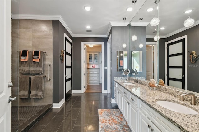 bathroom with a tile shower, crown molding, and vanity