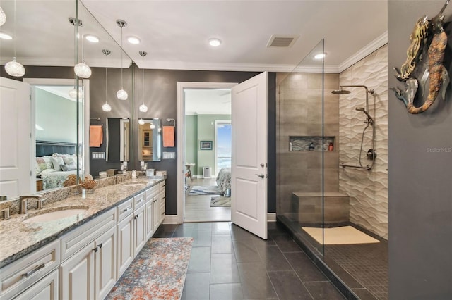 bathroom with tile patterned flooring, vanity, ornamental molding, and tiled shower