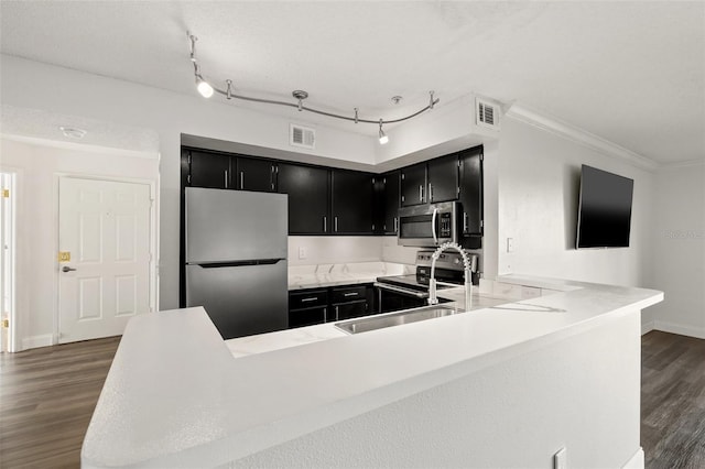 kitchen featuring crown molding, a textured ceiling, kitchen peninsula, dark hardwood / wood-style flooring, and stainless steel appliances