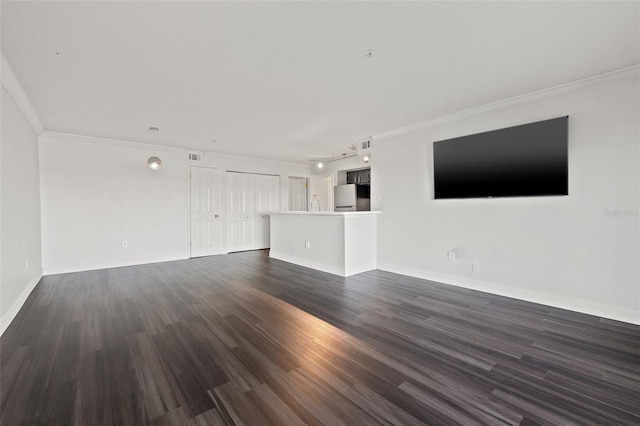 unfurnished living room with track lighting, crown molding, and dark wood-type flooring