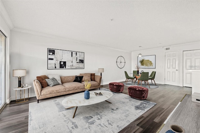 living room with dark wood-type flooring, a textured ceiling, and crown molding