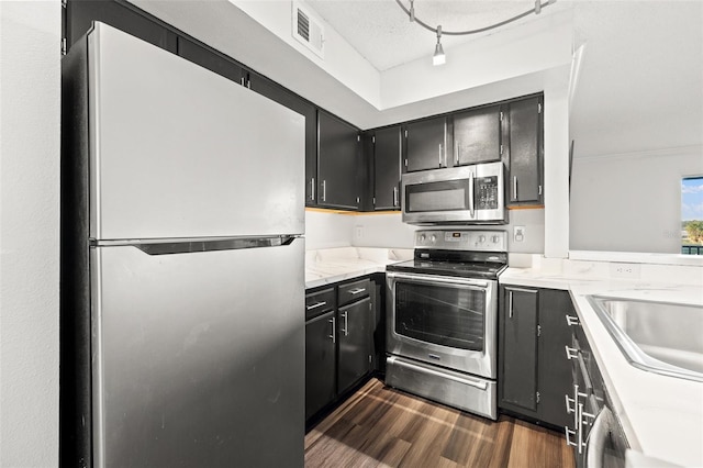 kitchen featuring a textured ceiling, stainless steel appliances, sink, rail lighting, and dark hardwood / wood-style floors