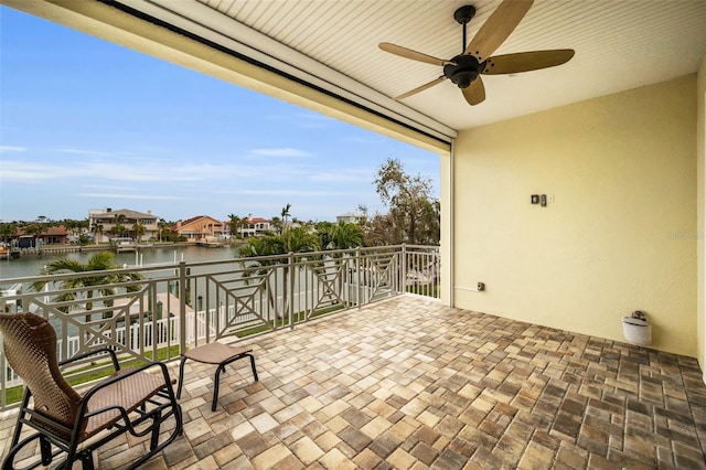 view of patio / terrace featuring a water view, ceiling fan, and a balcony