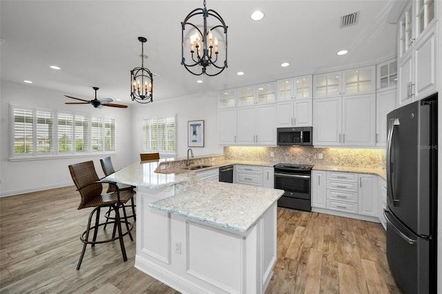 kitchen with ceiling fan with notable chandelier, white cabinetry, stainless steel appliances, and decorative light fixtures