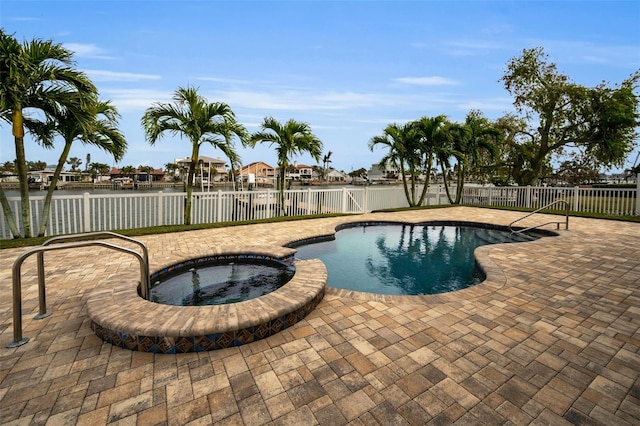 view of pool featuring an in ground hot tub, a water view, and a patio area