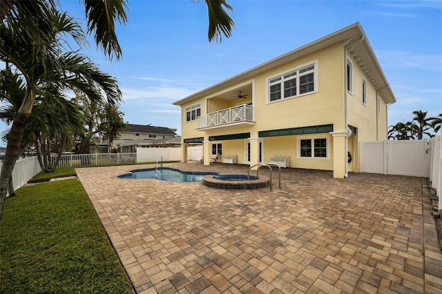 rear view of house featuring a pool with hot tub, ceiling fan, a balcony, and a patio