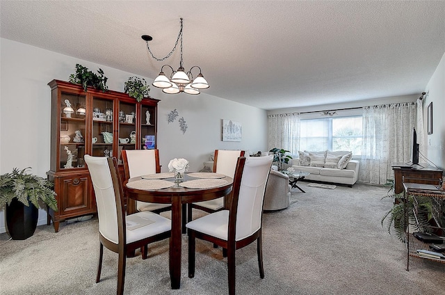 carpeted dining room with a textured ceiling and a chandelier