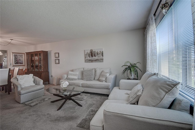 carpeted living room featuring a notable chandelier and a textured ceiling