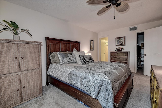 bedroom featuring a textured ceiling, ceiling fan, and light carpet