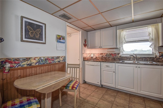 kitchen with dishwasher, a drop ceiling, white cabinetry, and sink