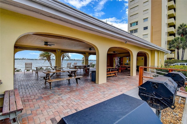 view of patio featuring a grill, ceiling fan, and a water view