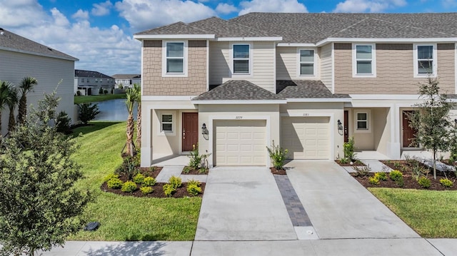 view of front facade with a front lawn, a garage, and a water view