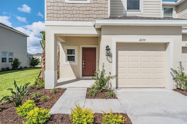 entrance to property featuring a garage and a lawn