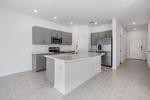 kitchen featuring stainless steel appliances, sink, light tile patterned floors, and an island with sink