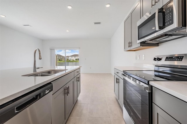 kitchen with stainless steel appliances, sink, light tile patterned floors, and gray cabinets