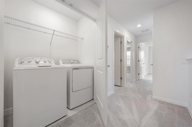 clothes washing area with light colored carpet and washing machine and clothes dryer