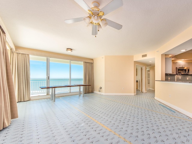 unfurnished living room with a water view, ceiling fan, and light colored carpet