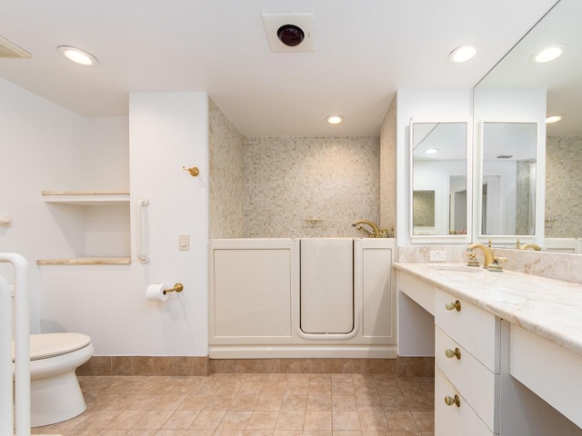 bathroom with a washtub, vanity, and toilet