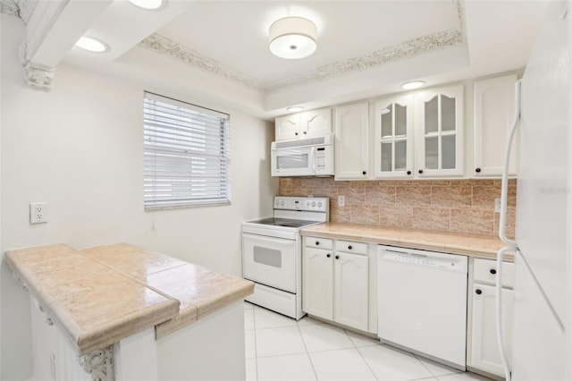 kitchen with light tile patterned floors, white cabinetry, kitchen peninsula, backsplash, and white appliances