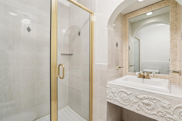 bathroom featuring a shower with shower door, tile walls, and vanity