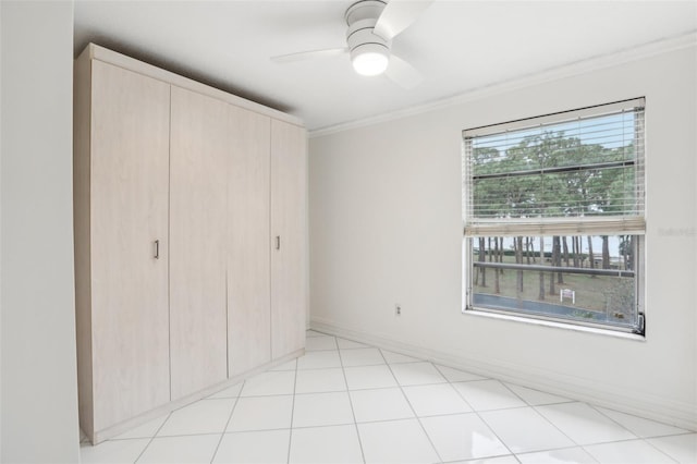 unfurnished bedroom with ceiling fan, a closet, crown molding, and multiple windows