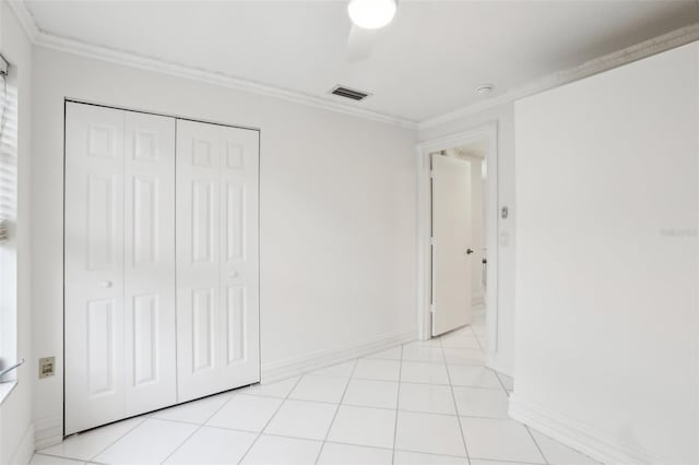 unfurnished bedroom featuring ceiling fan, a closet, light tile patterned flooring, and ornamental molding