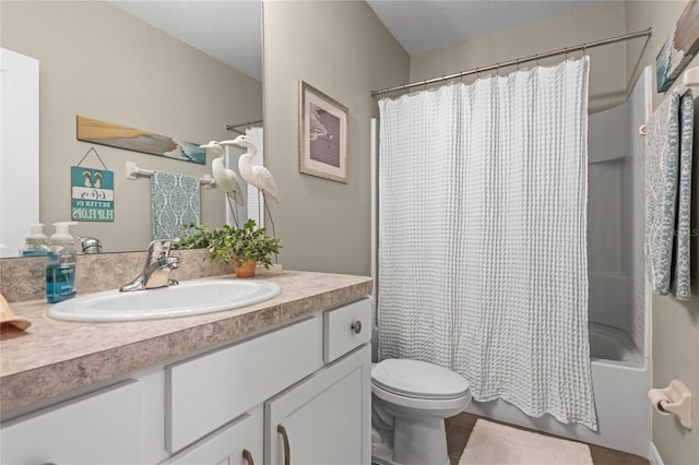 full bathroom featuring shower / tub combo with curtain, vanity, a textured ceiling, and toilet