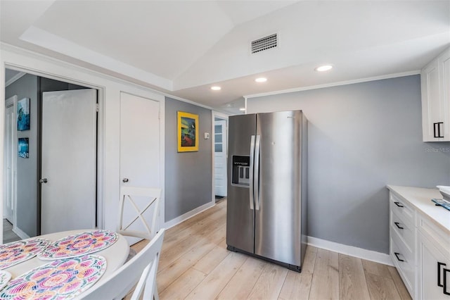 kitchen with light hardwood / wood-style flooring, stainless steel fridge with ice dispenser, white cabinetry, and vaulted ceiling