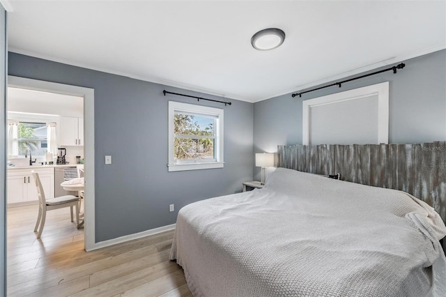 bedroom with sink, light hardwood / wood-style floors, and multiple windows