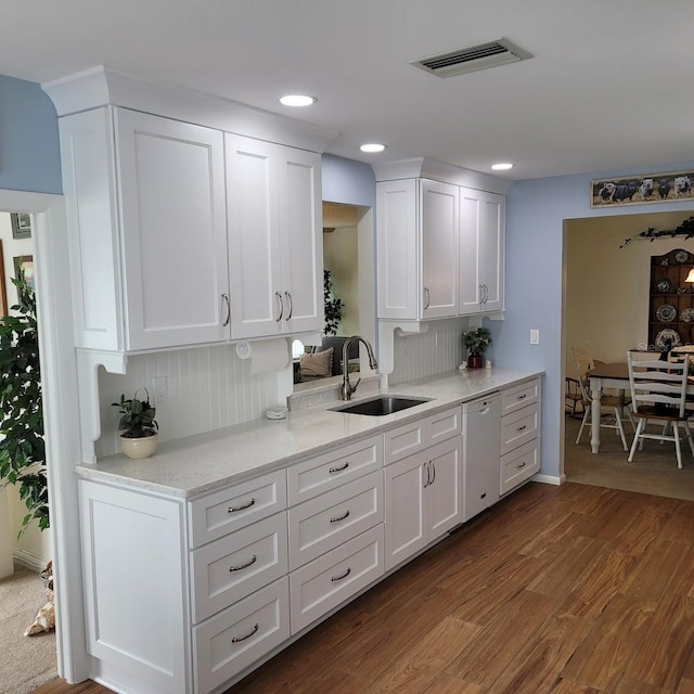 kitchen with hardwood / wood-style floors, dishwasher, white cabinetry, and sink