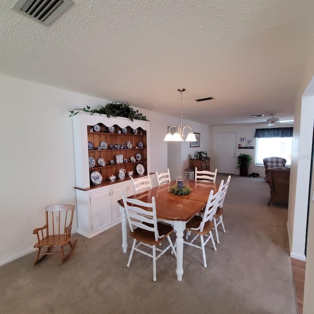 dining area with ceiling fan with notable chandelier, a textured ceiling, and light carpet