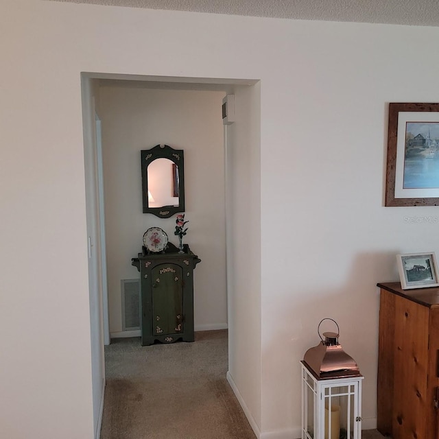 hallway featuring a textured ceiling and light colored carpet