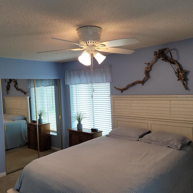 carpeted bedroom with a textured ceiling, ceiling fan, and a closet