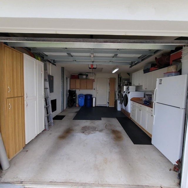 garage featuring separate washer and dryer, white fridge, and a garage door opener