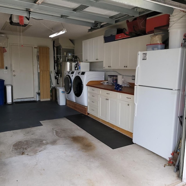 garage featuring white refrigerator, washer and clothes dryer, and a garage door opener