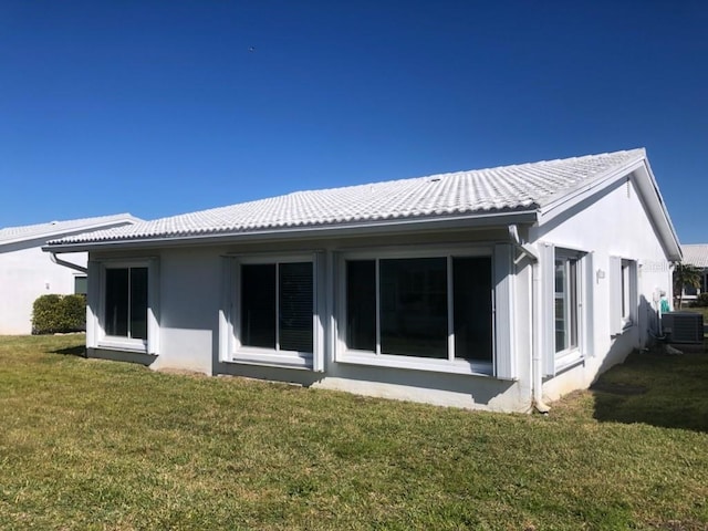 rear view of house with a lawn and central AC