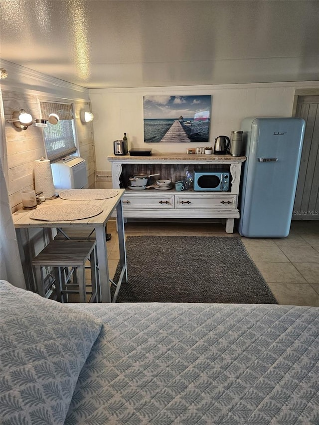 kitchen with tile patterned flooring, white cabinets, and fridge