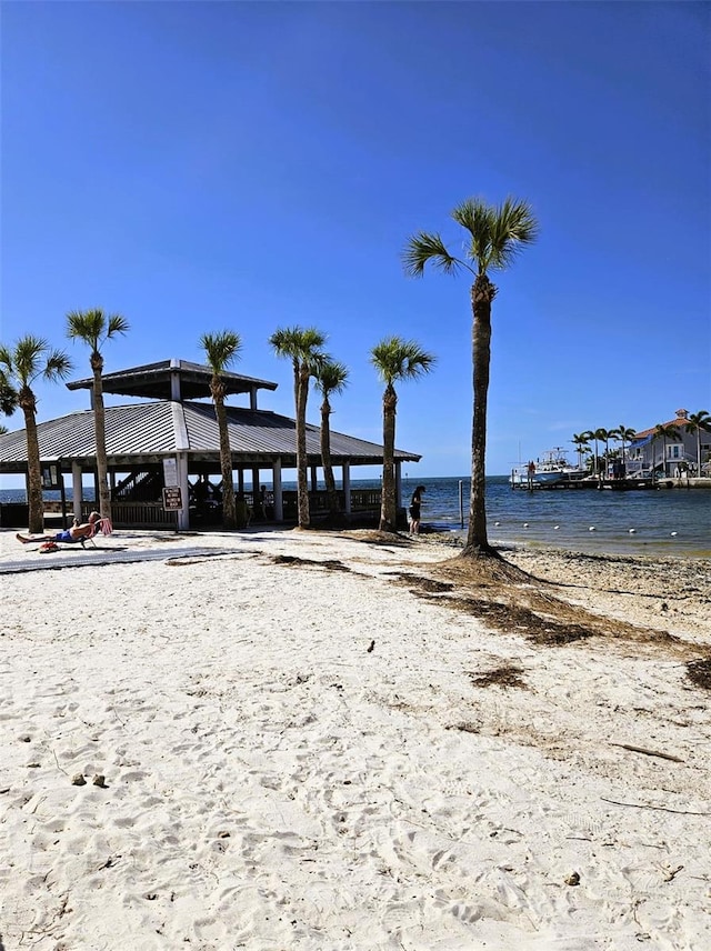 view of dock with a water view and a beach view