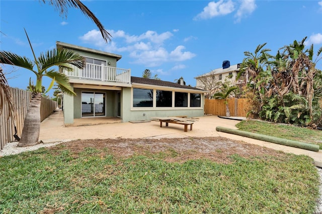 rear view of property featuring a patio area, a balcony, and a yard