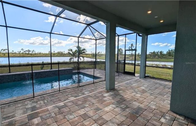 view of swimming pool with a water view, glass enclosure, a patio area, and a lawn