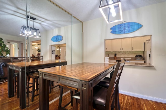 dining space with a textured ceiling and dark hardwood / wood-style floors