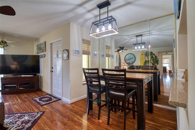 dining area with ceiling fan, wood-type flooring, and a textured ceiling