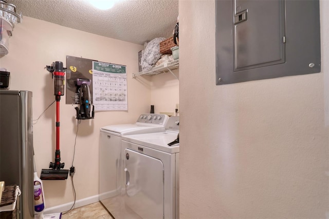 washroom featuring light tile patterned floors, separate washer and dryer, a textured ceiling, and electric panel