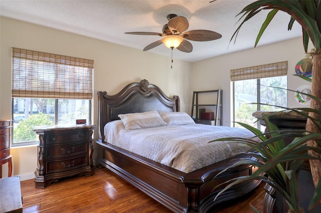 bedroom with ceiling fan, multiple windows, and hardwood / wood-style floors