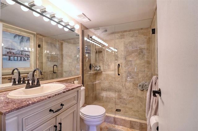 bathroom featuring a shower with shower door, toilet, and vanity