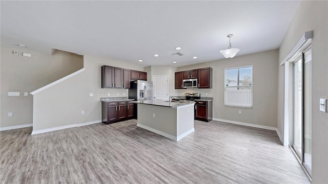 kitchen featuring decorative light fixtures, a center island with sink, light hardwood / wood-style flooring, stainless steel appliances, and dark brown cabinets