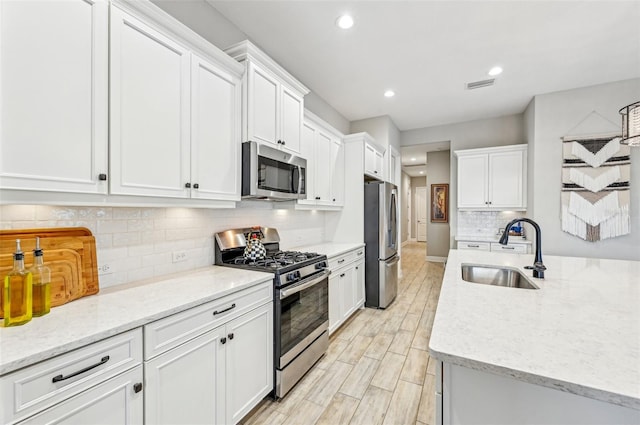 kitchen featuring sink, white cabinetry, tasteful backsplash, light stone counters, and stainless steel appliances